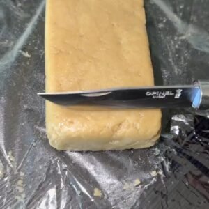 T-BONE HASH By TENCO premium solventless static hash rectangular block being sliced with Opinel knife on plastic wrap