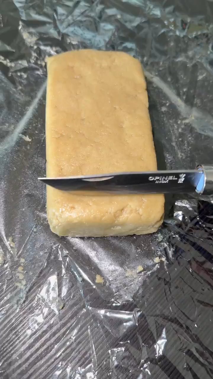 T-BONE HASH By TENCO premium solventless static hash rectangular block being sliced with Opinel knife on plastic wrap